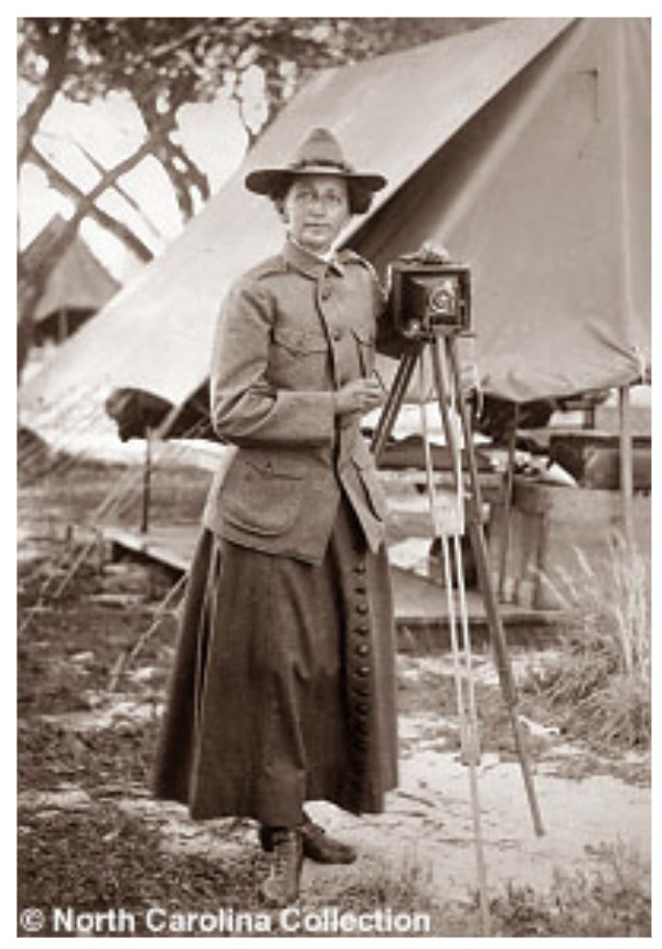 Bayard Wootten standing beside a large camera on a tripod.