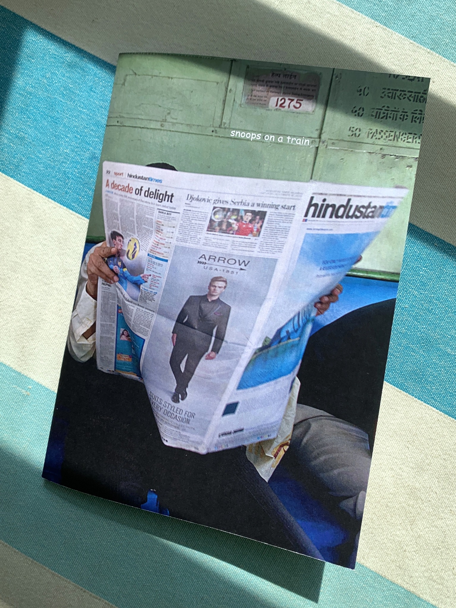 Cover of Ritesh Uttamchandani's train zine showing a passenger reading a newspaper on a train.